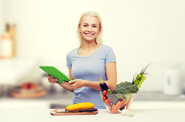 Image showing smiling woman with tablet pc cooking vegetables 