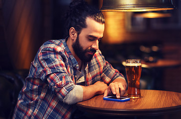 Image showing man with smartphone and beer texting at bar