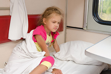 Image showing The girl on the train sleepily gets out of bed on the lower place in the second-class compartment wagon