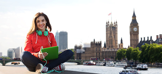 Image showing happy young woman with tablet pc and headphones