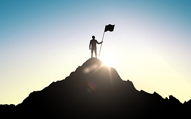 Image showing silhouette of businessman with flag on mountain