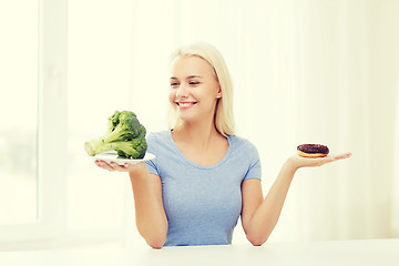 Image showing smiling woman with broccoli and donut at home