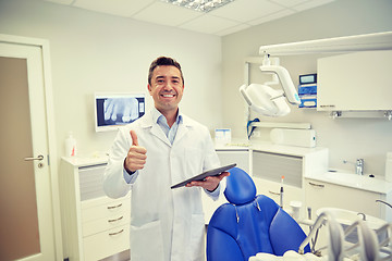 Image showing happy dentist showing thumbs up with tablet pc