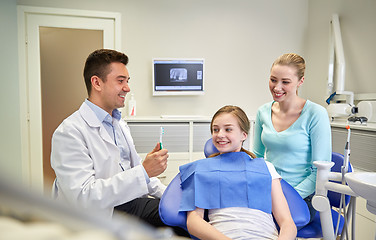 Image showing happy dentist showing toothbrush to patient girl