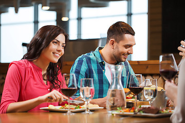 Image showing happy couple with friends eating at restaurant