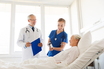 Image showing doctor giving medicine to senior woman at hospital