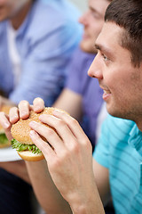 Image showing close up of friends eating hamburgers at home