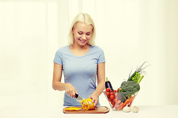 Image showing smiling young woman chopping vegetables at home