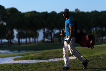 Image showing golfer  walking and carrying golf  bag at beautiful sunset