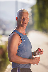 Image showing senior jogging man drinking fresh water from bottle