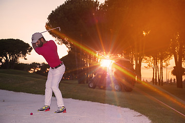 Image showing golfer hitting a sand bunker shot on sunset