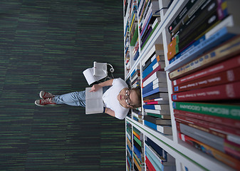 Image showing female student study in library, using tablet and searching for 