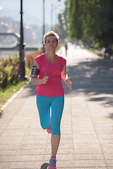 Image showing jogging woman setting phone before jogging