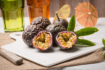 Image showing Passion fruits on white ceramic tray on wooden table background.