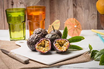 Image showing Passion fruits on white ceramic tray on wooden table background.