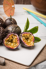 Image showing Passion fruits on white ceramic tray on wooden table background.