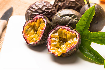 Image showing Passion fruits on white ceramic tray on wooden table background.