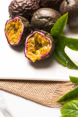 Image showing Passion fruits on white ceramic tray on wooden table background.