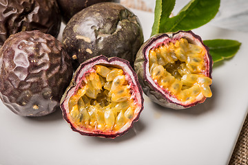 Image showing Passion fruits on white ceramic tray on wooden table background.