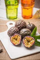 Image showing Passion fruits on white ceramic tray on wooden table background.