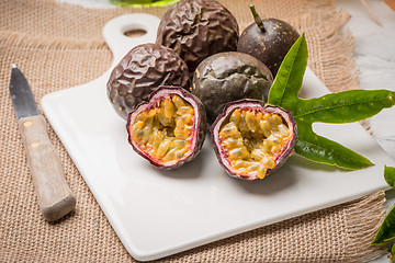 Image showing Passion fruits on white ceramic tray on wooden table background.