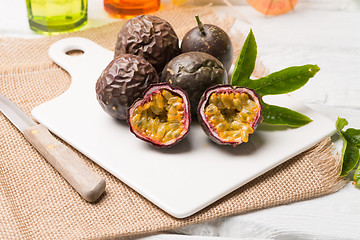 Image showing Passion fruits on white ceramic tray on wooden table background.