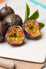 Image showing Passion fruits on white ceramic tray on wooden table background.