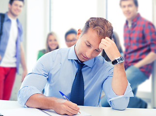 Image showing handsome teacher writing in notebook