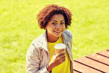 Image showing smiling african woman drinking coffee outdoors 