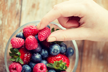 Image showing close up of woman hands with berries in glass bowl