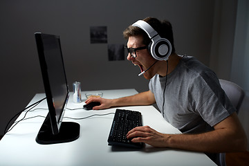 Image showing man in headset playing computer video game at home