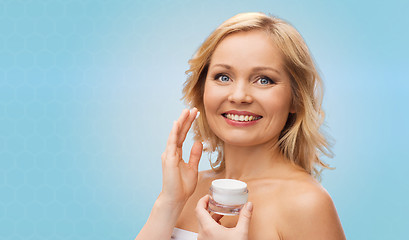 Image showing happy woman applying cream to her face