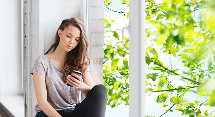 Image showing sad pretty teenage girl with smartphone texting