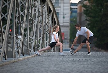 Image showing couple warming up and stretching before jogging