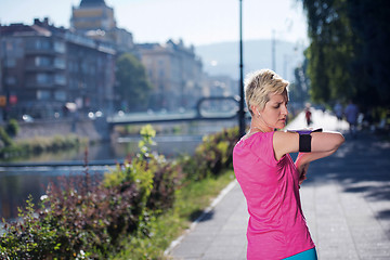 Image showing jogging woman setting phone before jogging