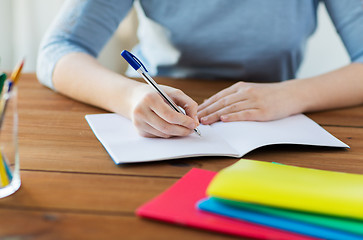 Image showing close up of student writing to notebook at home