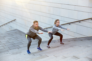 Image showing couple doing squats on city street stairs