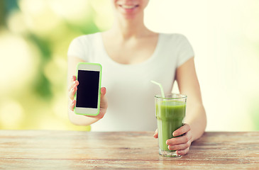 Image showing close up of woman with smartphone and green juice