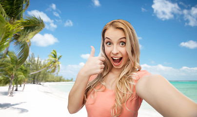 Image showing happy woman taking selfie and showing thumbs up