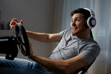 Image showing man playing car racing video game at home