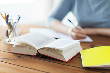 Image showing close up of student with book and notebook at home