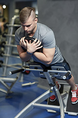 Image showing young man flexing back muscles on bench in gym