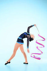 Image showing The girl doing gymnastics dance with colored ribbon on a blue background