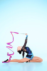 Image showing The girl doing gymnastics dance with colored ribbon on a blue background