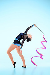 Image showing The girl doing gymnastics dance with colored ribbon on a blue background