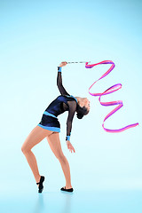 Image showing The girl doing gymnastics dance with colored ribbon on a blue background