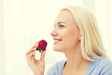 Image showing happy woman eating strawberry at home