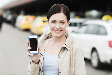 Image showing smiling woman showing smartphone over taxi in city