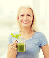 Image showing smiling woman drinking juice or shake at home