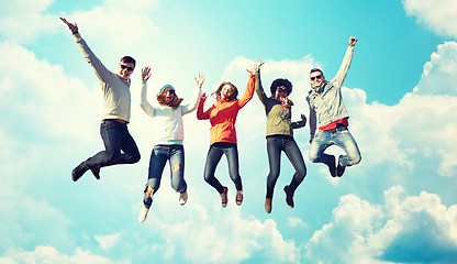 Image showing smiling friends in sunglasses jumping high